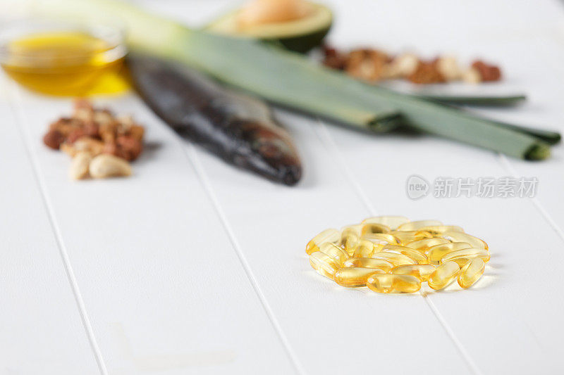 欧米茄3-6-9鱼油黄色软凝胶木制白板上质朴的桌子。omega - 3的食物来源是模糊的。鱼，鳄梨，橄榄油，核桃，杏仁，韭菜。健康饮食,饮食